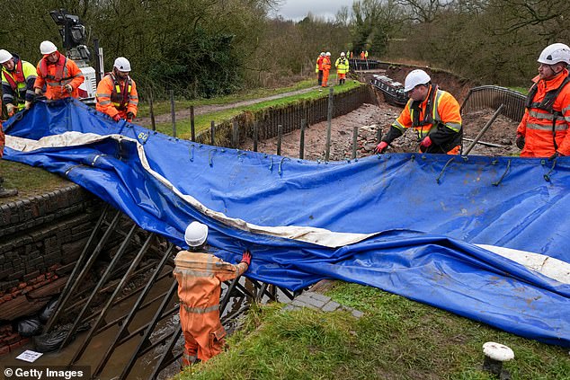 Workers build a dam as stranded canal boats wait to be lifted from the bed of the Llangollen Canal