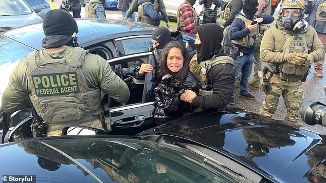 The woman clutched onto the driver's side door of her car as multiple agents dragged her onto the ground