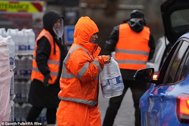 A worker hands over bottled water at a water station in East Grinstead, after bad weather was blamed for more water outages in Kent and parts of Sussex