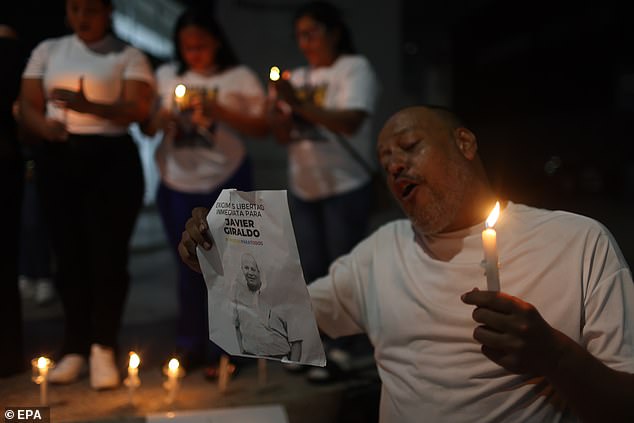 A man holds a sign and a candle during a vigil at El Helicoide in Caracas, Venezuela, January 13 2026