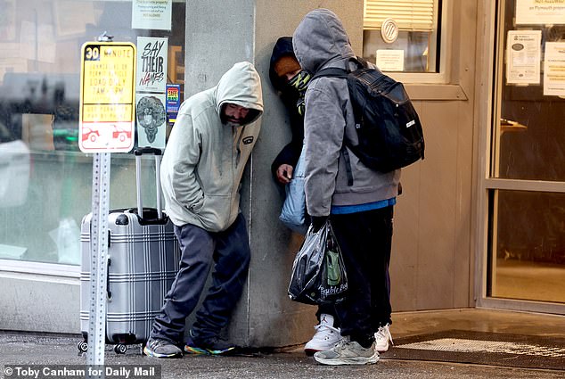 Addicts are seen lingering near a Downtown Seattle doorway, where many end up while taking cover from the rain