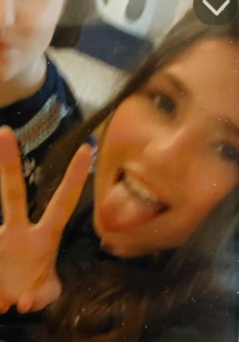 Person making a peace sign and sticking out their tongue.