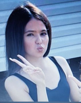 Woman making a kissing face and peace sign.