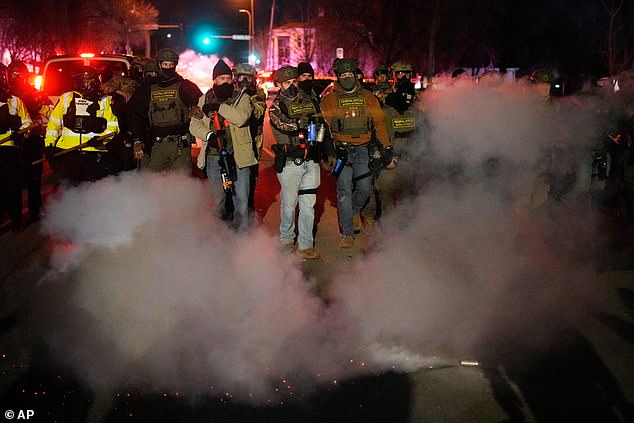 A federal law enforcement officer deploys pepper spray during a protest after a shooting on Wednesday