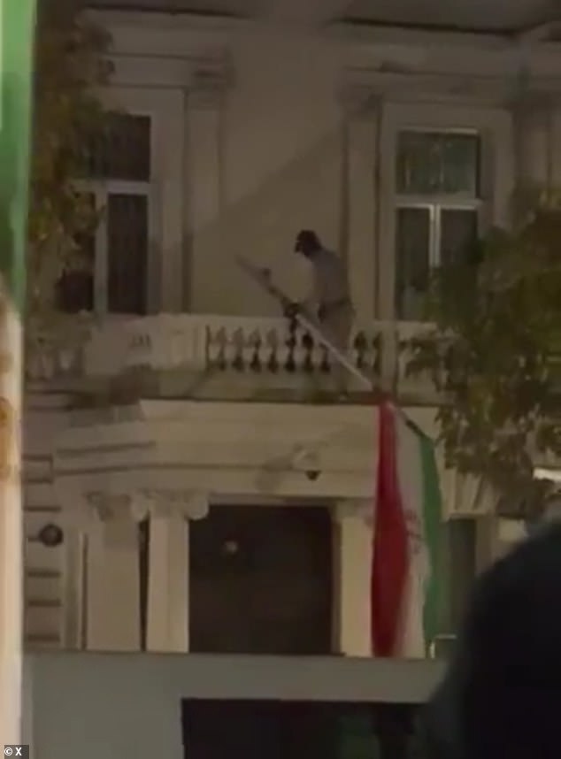 Police violently clashed with protesters outside the embassy yesterday after an activist climbed the building and took down the Islamic Republic's flag. Pictured: An activist removing the Iranian flag from the balcony
