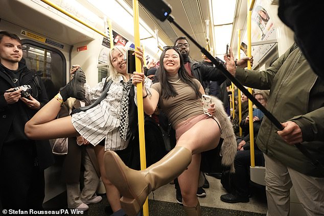 Two women stand on a train as they take part in the No Trousers Tube Ride on Sunday