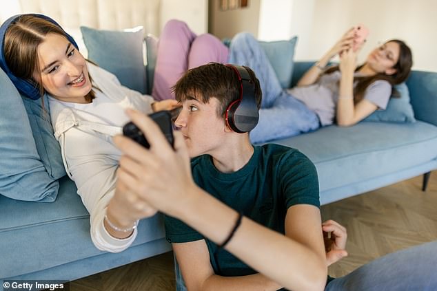 Medical professionals say screen time and harmful online content have dangerous effects on their wellbeing. Stock image shows teenagers using mobile phones