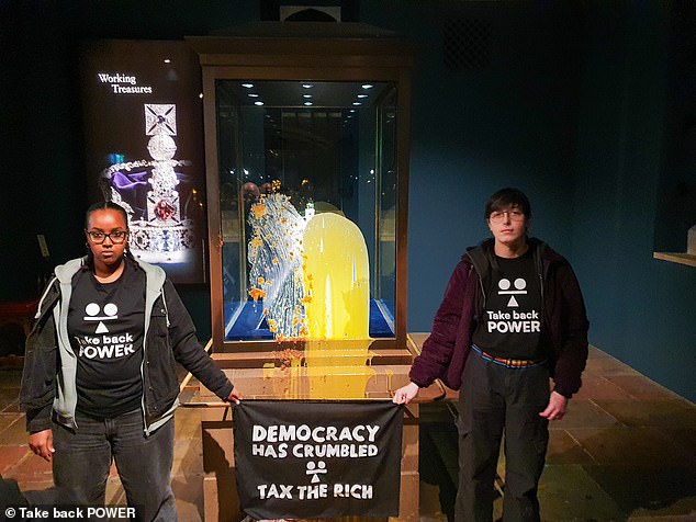 Two of those involved unfurled a banner saying 'democracy has crumbled, tax the rich' after targeting the glass case