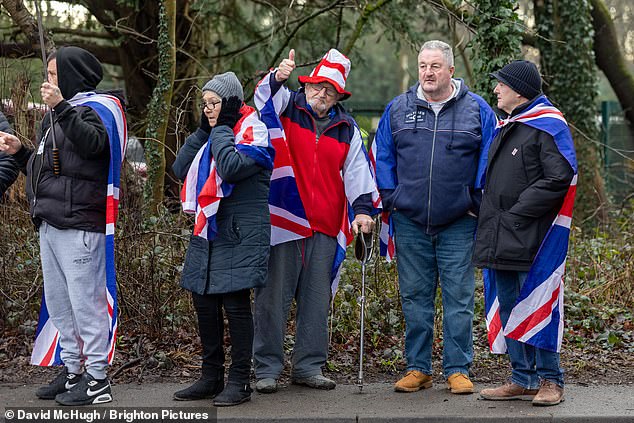 A group of locals adorned in British flags watch as the marchers make their way through the town