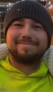 Headshot of a man with a dark knit hat, light beard, and neon green shirt.