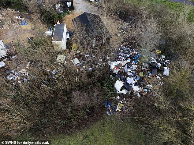There are several fly tips in the countryside surrounding the substation. Here, piles of waste cover an area of woodland next to a group of prefabricated huts