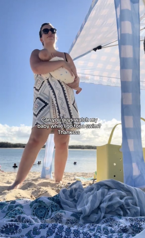 A woman in sunglasses and a patterned cover-up holds a baby on a beach under a canopy, with text asking viewers to watch her baby.