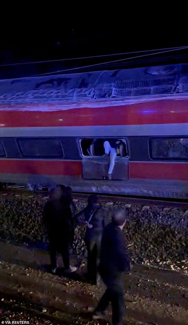 A passenger is photographed exiting one of the derailed trains as first responders search through the wreckage near Cordoba, on Sunday