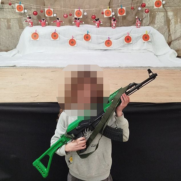 Another young child holds a large rifle during a lesson with the establishment, which denies it is a school