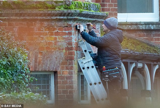 A workman measures up for the installation of new security lights on one of the red brick walls at Marsh Farm on January 13