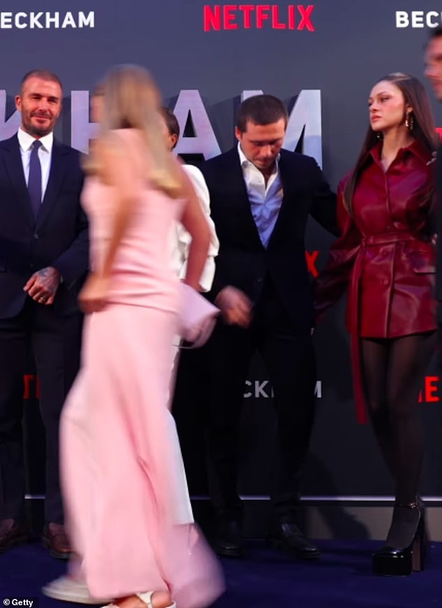 In the footage, Brooklyn reaches out of shot to encourage Nicola to join the group picture before she reluctantly moves in and then appears to shoot Victoria and David a tense glance