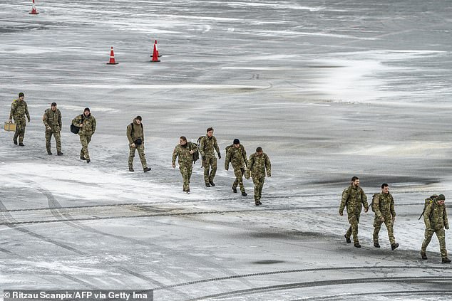 Danish soldiers walk across the frozen tarmac after arriving at Nuuk airport, Greenland