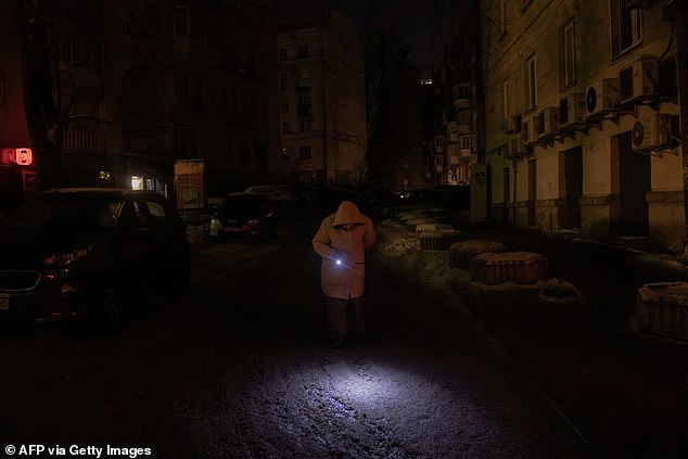 A person uses a torch to walk through a non-illuminated street during a power outage in Kyiv on January 19, 2026, following Russian missile and drone attacks on Ukrainian energy infrastructure amid the Russian invasion of Ukraine