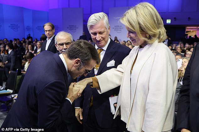 France's President Emmanuel Macron (2L) greets Queen Mathilde of Belgium (R) in front of King Philippe - Filip of Belgium (C) during the World Economic Forum