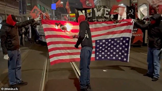 Masked protesters were filmed setting fire to a large US flag in the middle of the street