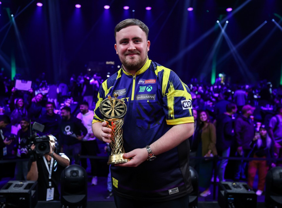 Luke Littler holding the Saudi Darts Masters trophy.