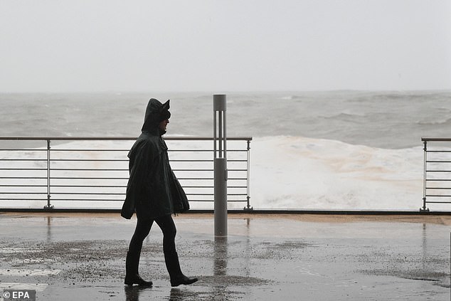 A person walks as waves hit the shore at Mazzeo beach in Taormina, on Sicily's eastern coast, southern Italy, 20 January 2026. Italy's Civil Protection Department issued a red alert for severe weather across Sardinia, Sicily, and Calabria on 20 January