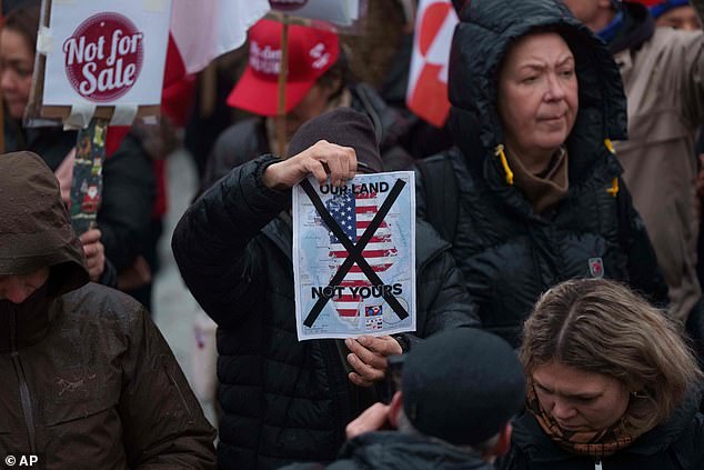A man holds a map of Greenland covered in the American flag crossed out with an X during a protest against Trump's policy towards Greenland in front of the US consulate in Nuuk, Greenland, January 17, 2026