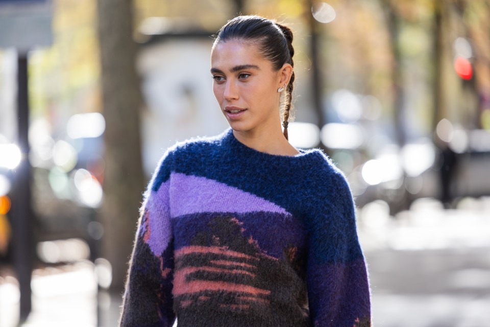 Ariadna Tapia wearing a purple, lilac, and brown knitted sweater.
