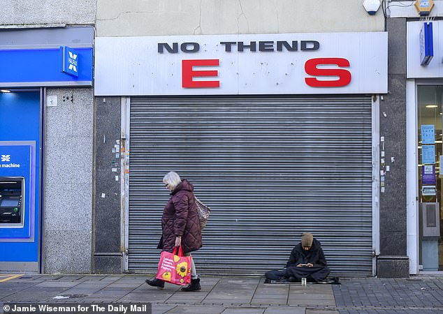Some shops are boarded up in the area, while homeless people sit on the streets