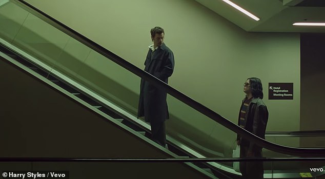 Harry looked very dapper in a white shirt with black lips printed across it, which he wore under a grey v-neck jumper and long navy trench coat