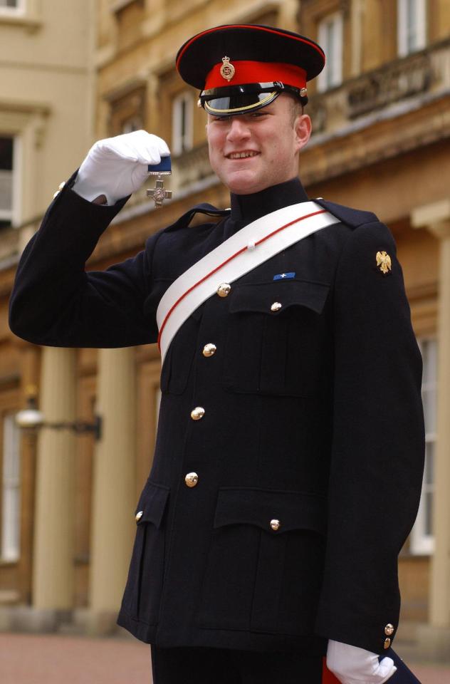 Christopher Finney wearing a military uniform and holding the George Cross medal.