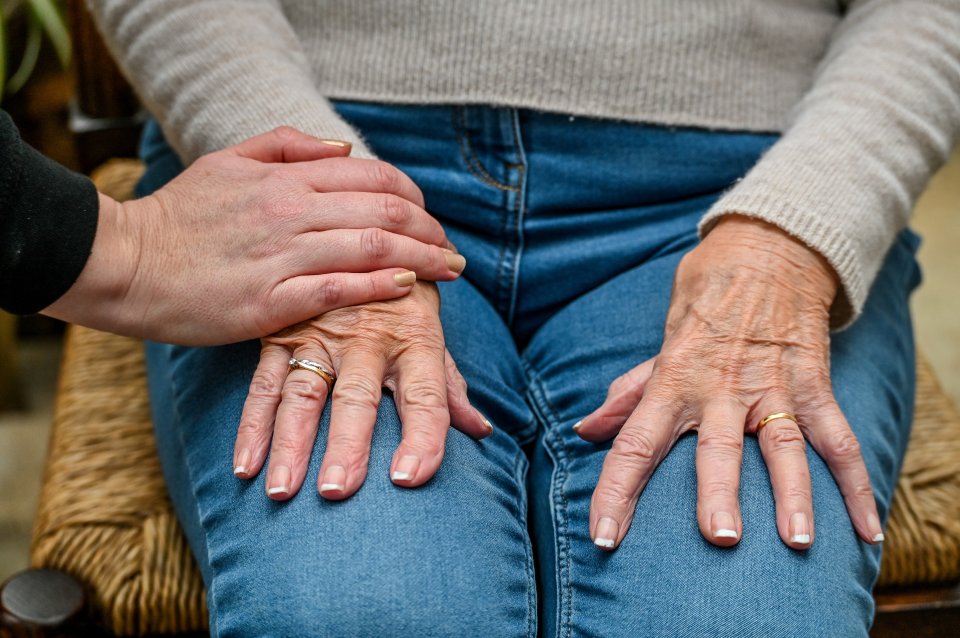A young hand placed on top of an elderly person's hand, who is wearing a ring.