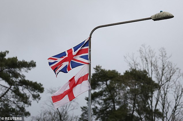 A British Union Jack national flag and the English flag of St. George attached to a lamp post beside an entrance to Crowborough army training camp