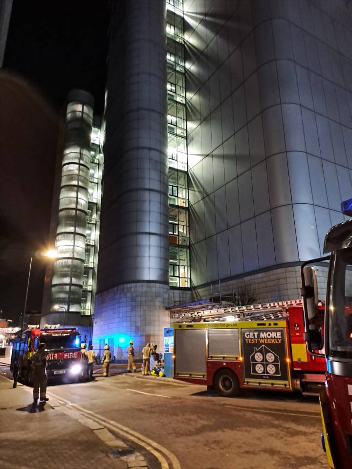 Firefighters and fire engines at a building at night.