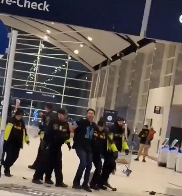 The man, who was wearing a black Detroit Lions jersey, was taken into custody by a horde of officers