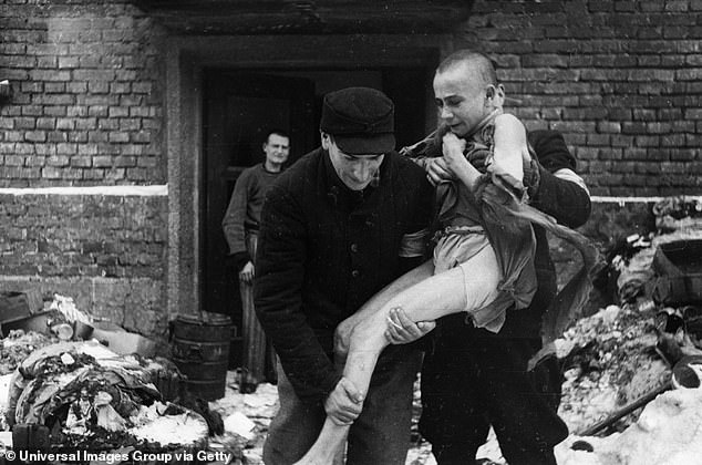 A 15-year-old Russian inmate, Ivan Dudnik, is helped out of Auschwitz by rescuers