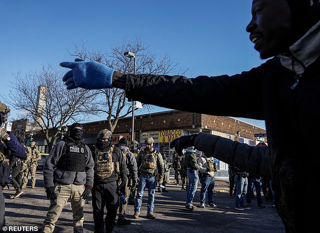 Protesters are blocking streets with dumpsters and restaurant furniture while shouting at agents, with the area still secured with police tape