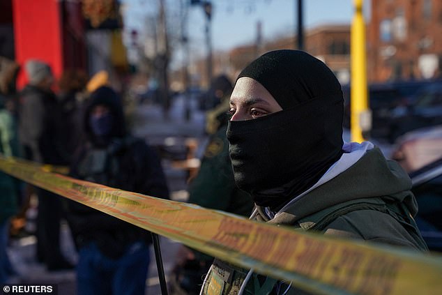A federal agent stands guard at the scene of a shooting involving federal immigration agents, in Whittier neighborhood, in South Minneapolis