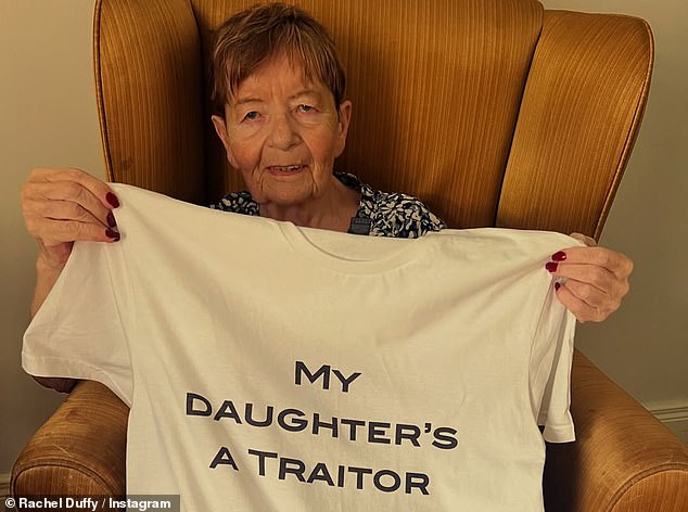 In a photograph, Rachel's mother Anne, who has dementia and was diagnosed with Parkinson's when she was in her 40s, is seen proudly holding up a T-shirt which says 'My daughter's a traitor' on the front