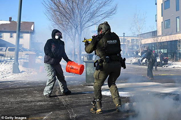 A federal agent and a protestor pictured face to face amidst widespread protests