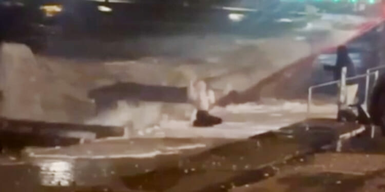 Moment woman is hit by crushing waves and nearly swept into sea while taking selfie during Storm Ingrid's fierce winds