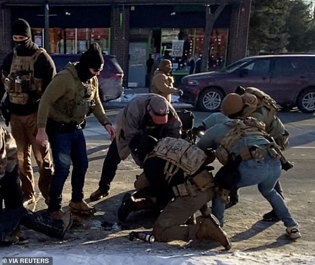 Multiple federal agents are seen surrounding Pretti as he is restrained on the pavement