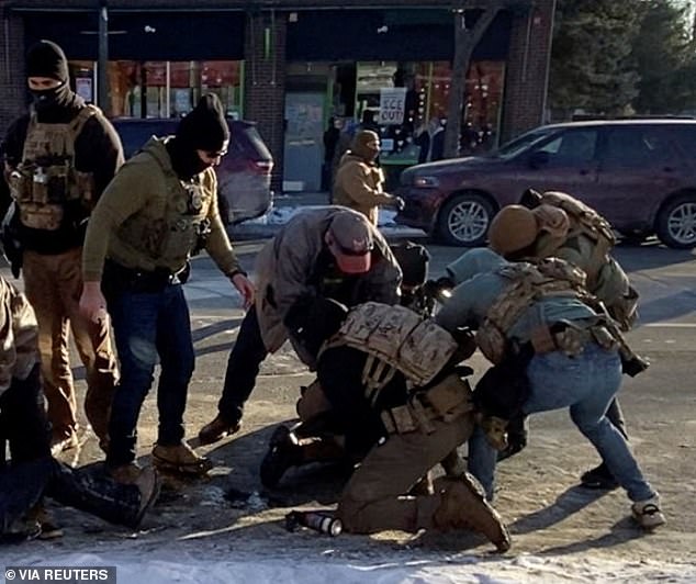 Multiple federal agents are seen surrounding Pretti as he is restrained on the pavement