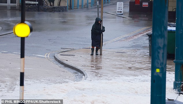 A walker clings on to a lamppost as Storm Ingrid hit Devon on Saturday
