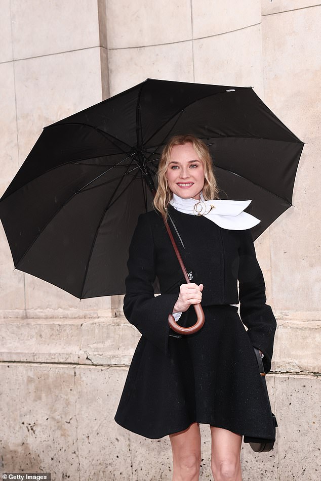 Keeping dry underneath a large black umbrella, Diane wore a black miniskirt and structured blazer