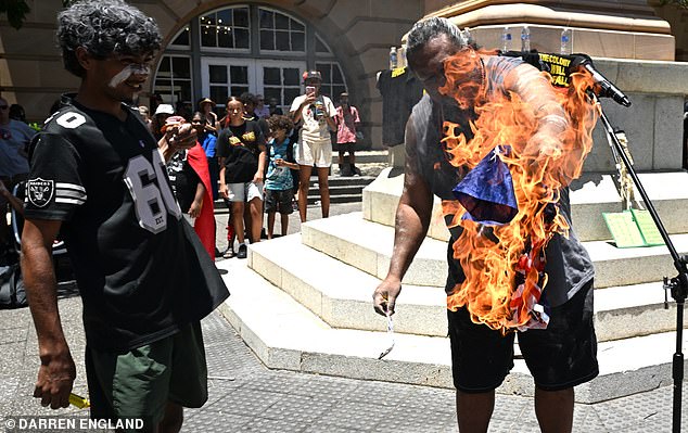 Protesters are seen burning an Australian flag during an Invasion Day rally in Brisbane, Monday, January 26, 2026. (AAP Image/Darren England) NO ARCHIVING