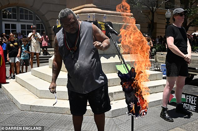 Protesters are seen burning an Australian flag during an Invasion Day rally in Brisbane, Monday, January 26, 2026. (AAP Image/Darren England) NO ARCHIVING