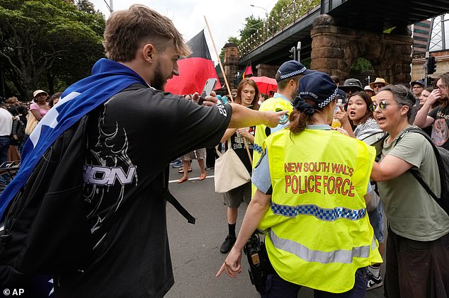 A man draped in an Australian flag, left, is involved in an altercation during a "Invasion Day" rally and match on Australia Day in Sydney, Monday, Jan. 26, 2026. (AP Photo/Rick Rycroft)