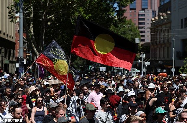 A man holds an Australian Aboriginal flag as protestors gather for an "Invasion Day" rally on Australia's national day, Australia Day, in Melbourne, Australia January 26, 2026. REUTERS/Hollie Adams REFILE - QUALITY REPEAT