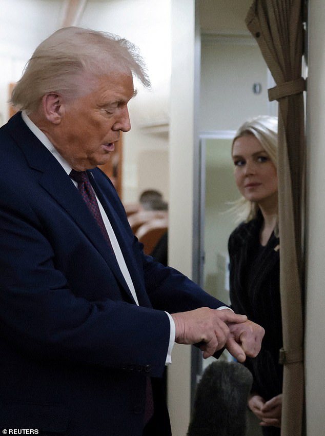 President Donald Trump points to his bruised left hand on board Air Force One Thursday as he returned to Washington, D.C. from Davos, Switzerland